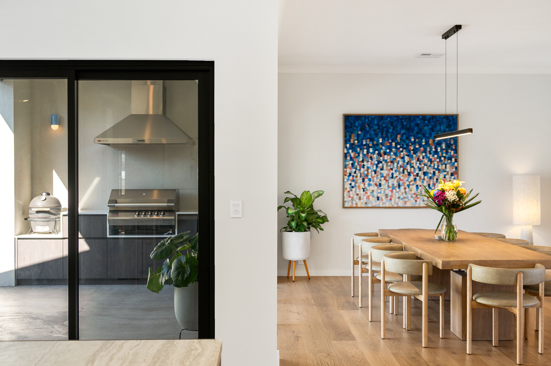 Interior of a Perth home with dining area and alongside it is a black framed door there is a new outdoor kitchen in the alfresco.