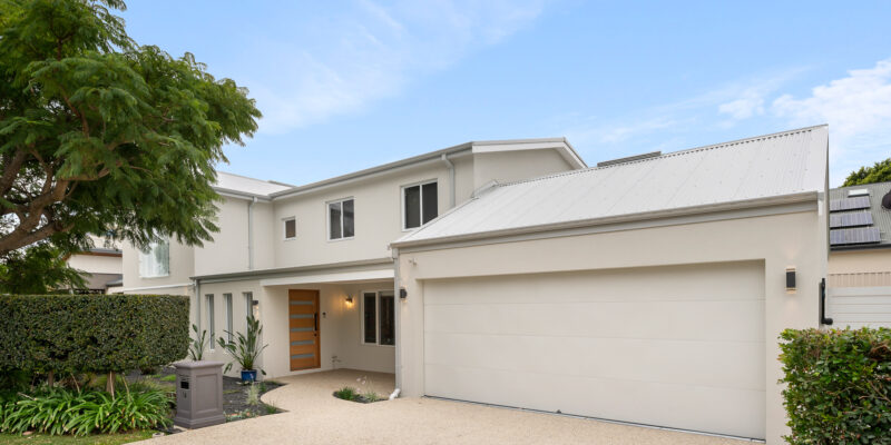 Newly renovated front of a Perth home, with double garage and driveway next to a lush garden.